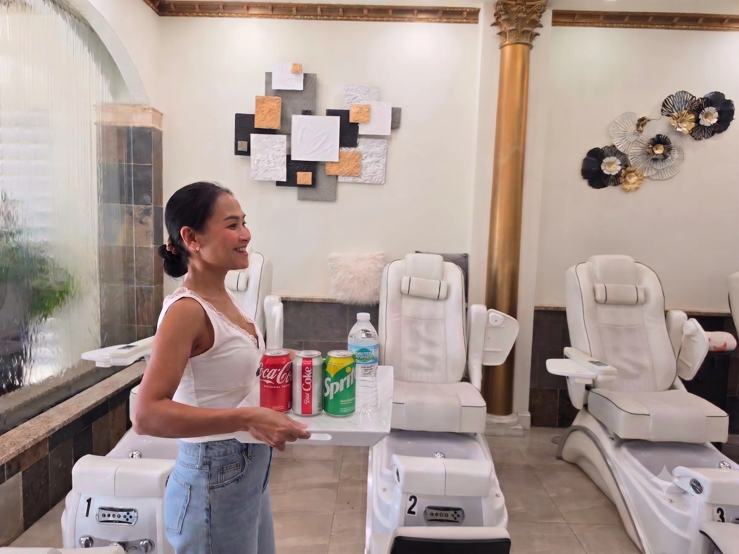 Elite Nail Spa team member offering complimentary soft drinks and bottled water beside the pedicure chairs